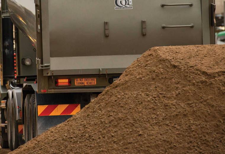 Rear view of a truck dumping a load of soil
