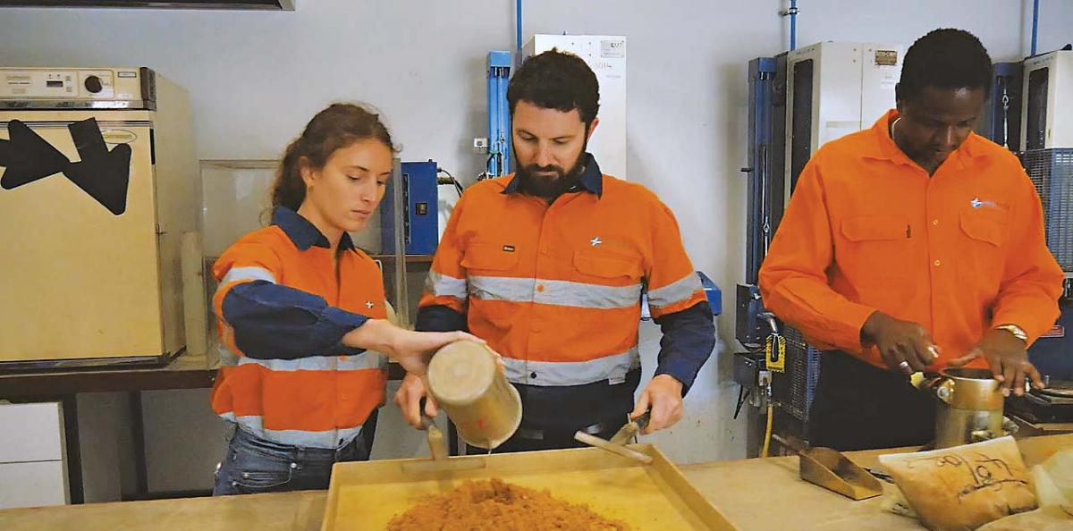 3 workers in high vis analysing soil samples