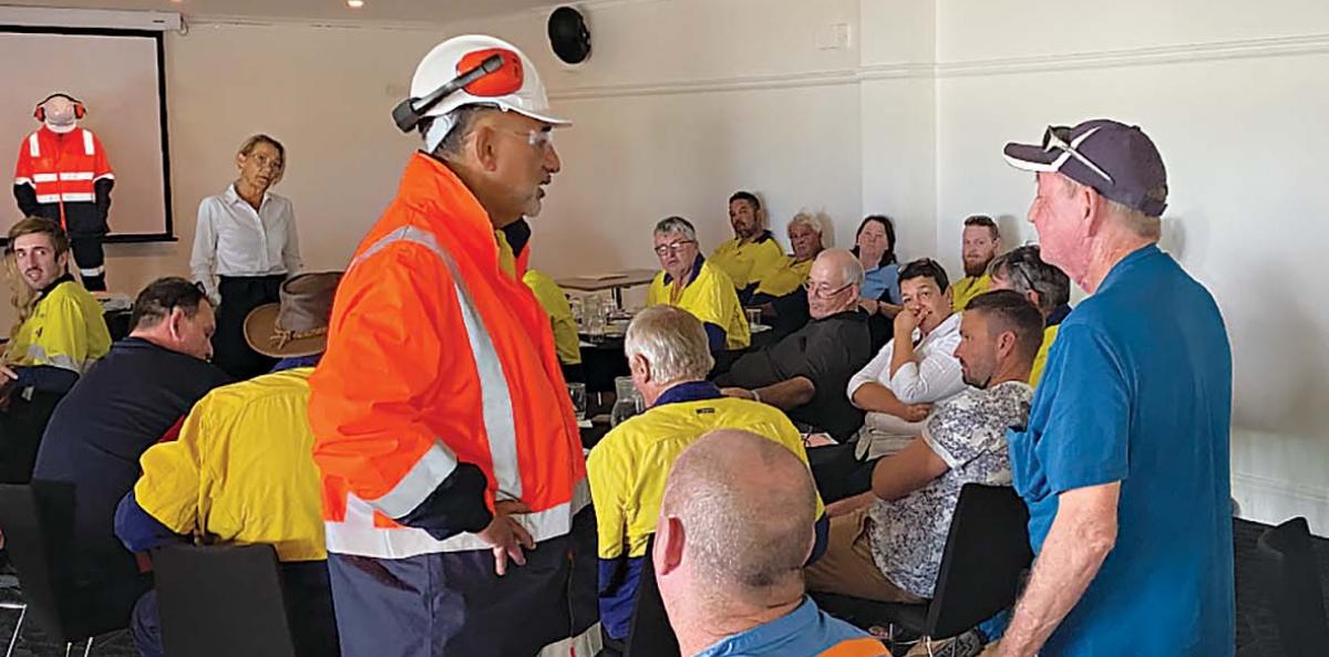 A group of workers in an office. Two are standing  and enacting a scene whilst the others look on.