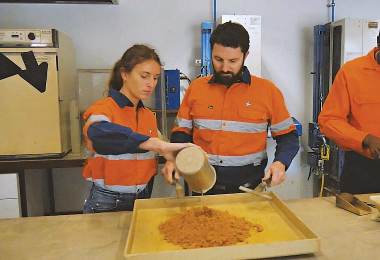 3 workers in high vis analysing soil samples