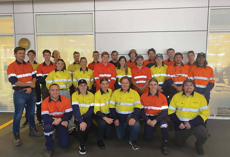 A group of workers wearing bright yellow and orange high vis gear. They are posed as a group.